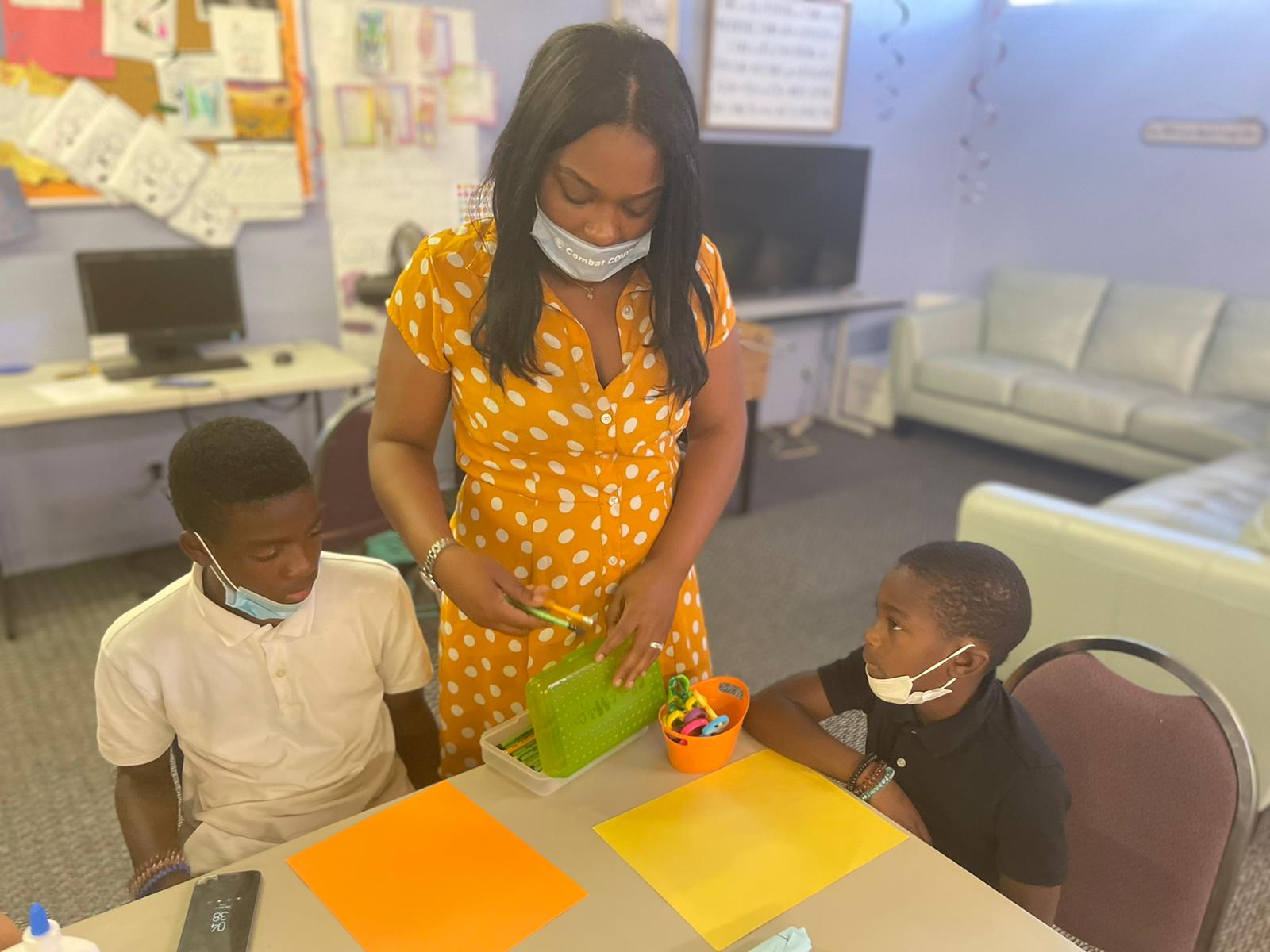 A Federation team member guiding two children through a hands-on youth activity